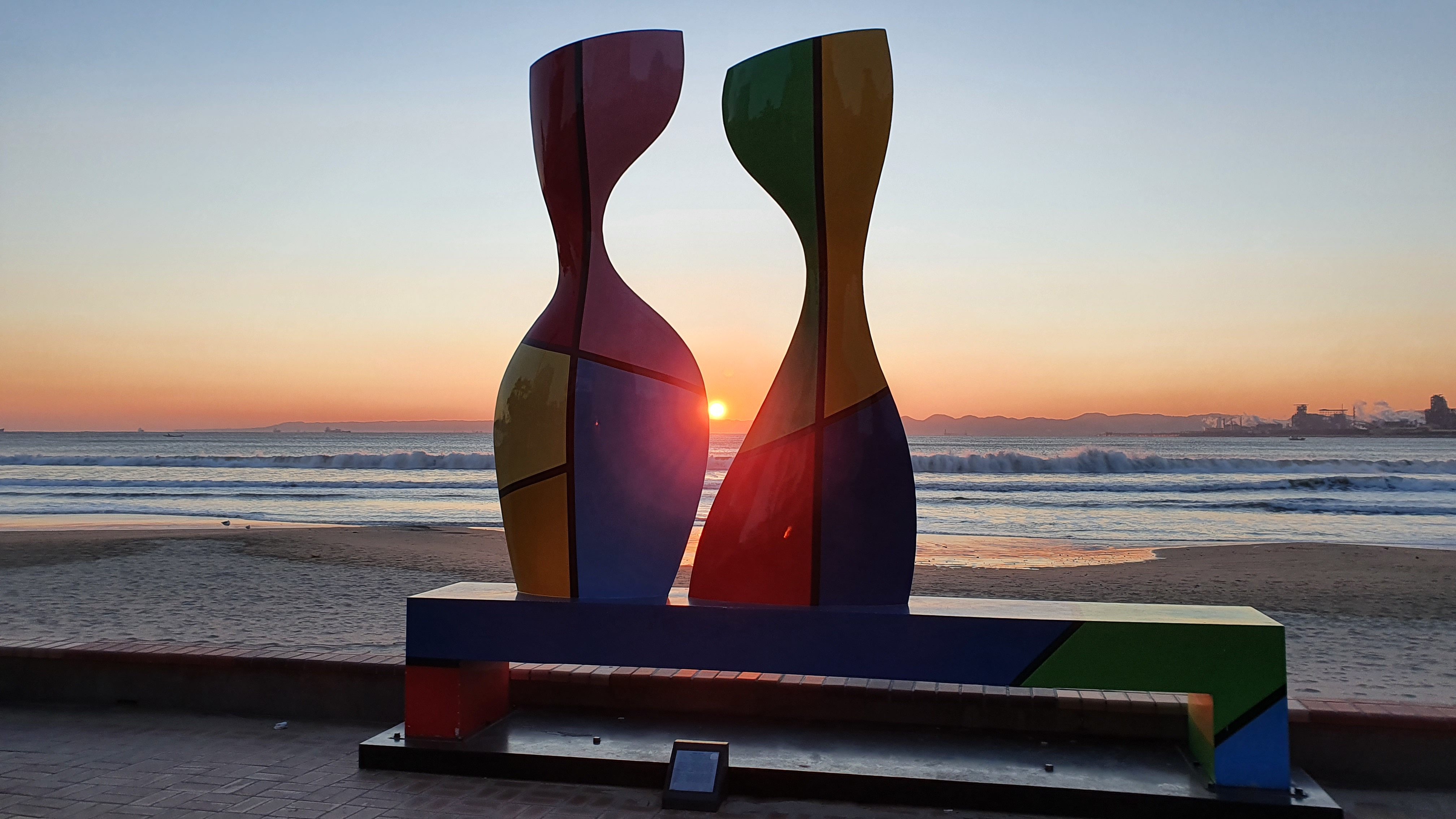 Sunrise behind statue on beach